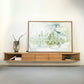 ÉTAUDORÉ San Salvatore wooden entertainment console with a framed abstract painting on a white wall